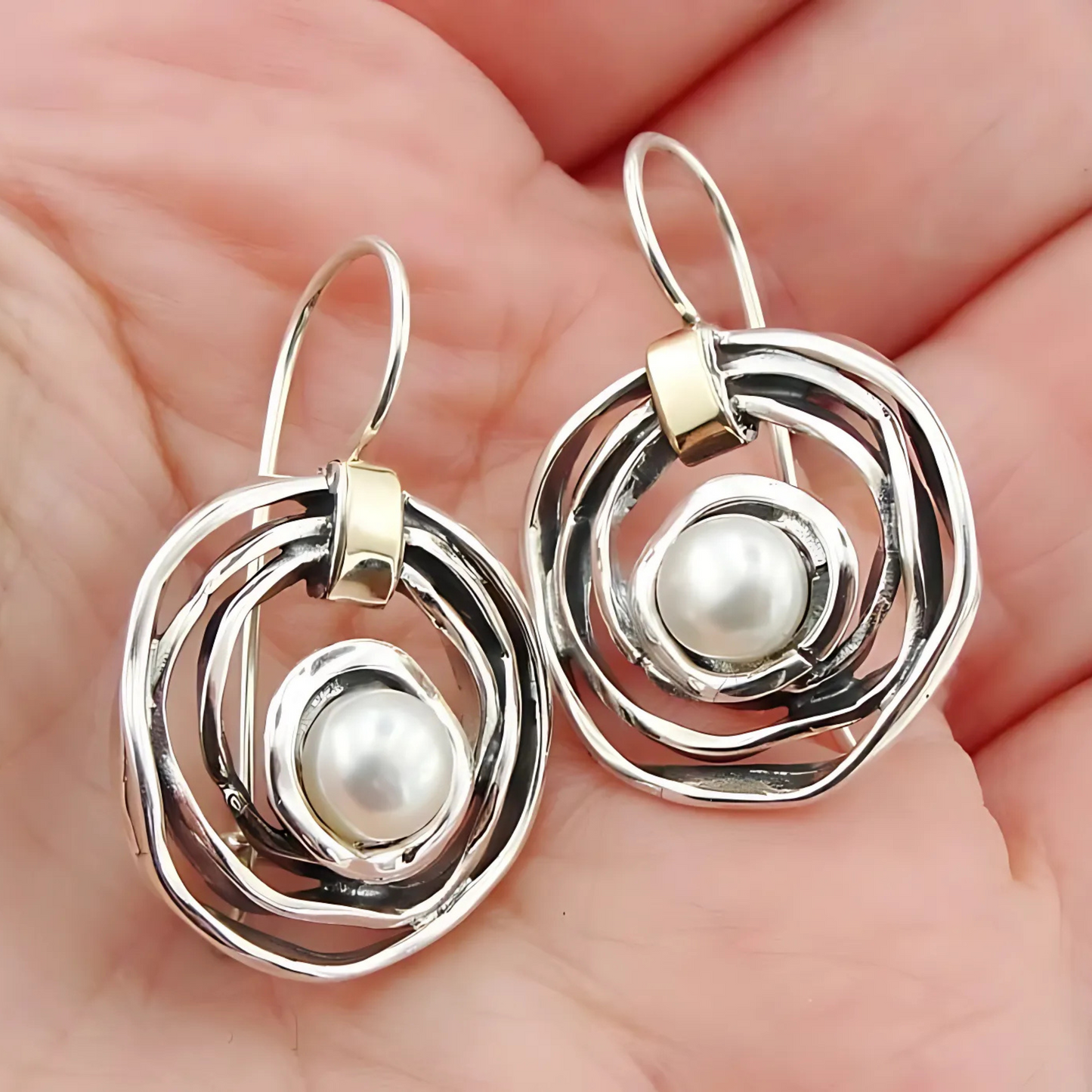 Elegant, handcrafted sterling silver earrings with a sophisticated open spiral design, featuring lustrous freshwater pearls as centerpieces and accented with delicate touches of yellow gold. These unique earrings, designed by Hadar Jewelry, blend modern aesthetics with timeless luxury, perfect for adding a refined, statement look to any ensemble.