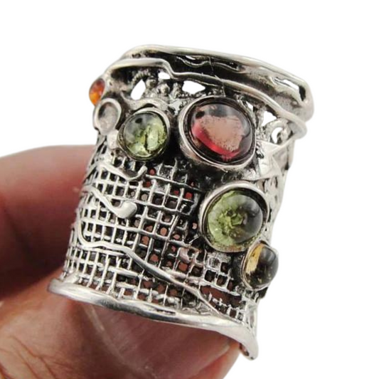 handcrafted sterling silver ring from the 'Nets' collection, featuring a wide silver band with intricate net detailing and six natural gemstones, including tourmaline, garnet, and citrine. The ring displays a unique, artistic design with vibrant green, red, and amber gemstones set against an oxidized silver background, creating a bold, textured statement piece