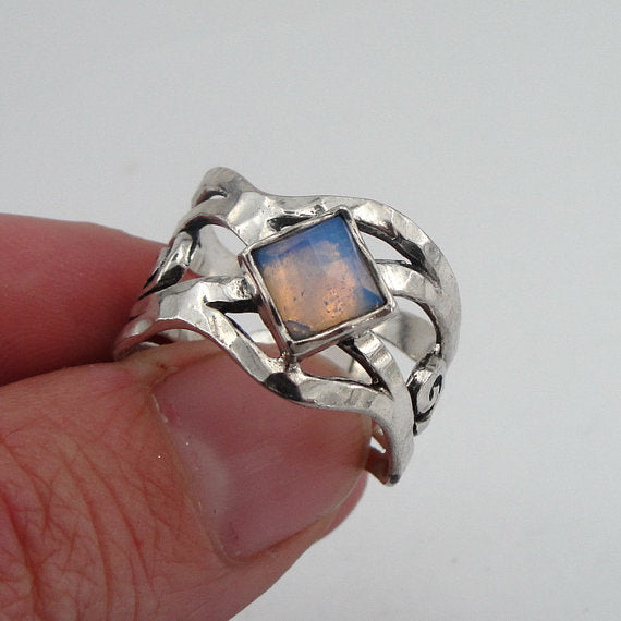 Sterling silver ring with an openwork design, featuring a square 6mm x 6mm Opalite gemstone. The ring’s unique sculptural pattern and solid silver band highlight the luminous, soft blue glow of the Opalite, creating an elegant, artistic piece by Hadar Jewelry