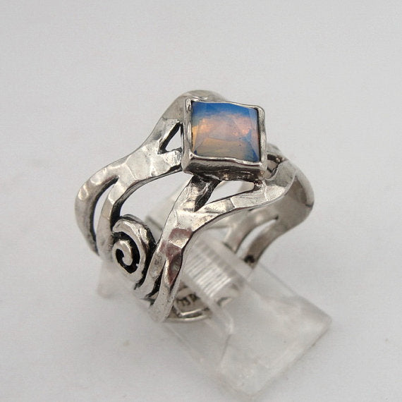 Sterling silver ring with an openwork design, featuring a square 6mm x 6mm Opalite gemstone. The ring’s unique sculptural pattern and solid silver band highlight the luminous, soft blue glow of the Opalite, creating an elegant, artistic piece by Hadar Jewelry