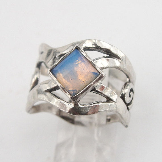 Sterling silver ring with an openwork design, featuring a square 6mm x 6mm Opalite gemstone. The ring’s unique sculptural pattern and solid silver band highlight the luminous, soft blue glow of the Opalite, creating an elegant, artistic piece by Hadar Jewelry