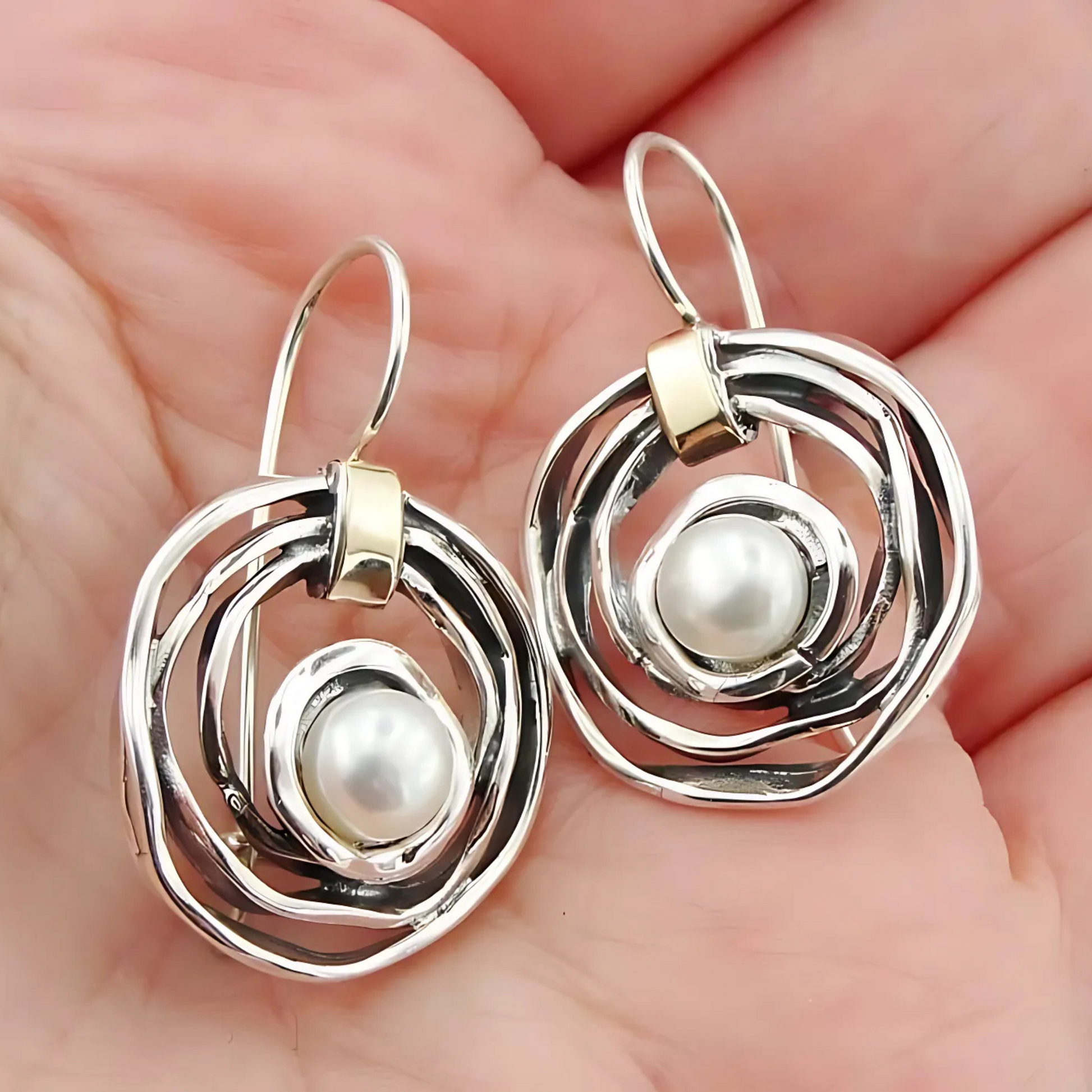 Elegant, handcrafted sterling silver earrings with a sophisticated open spiral design, featuring lustrous freshwater pearls as centerpieces and accented with delicate touches of yellow gold. These unique earrings, designed by Hadar Jewelry, blend modern aesthetics with timeless luxury, perfect for adding a refined, statement look to any ensemble.