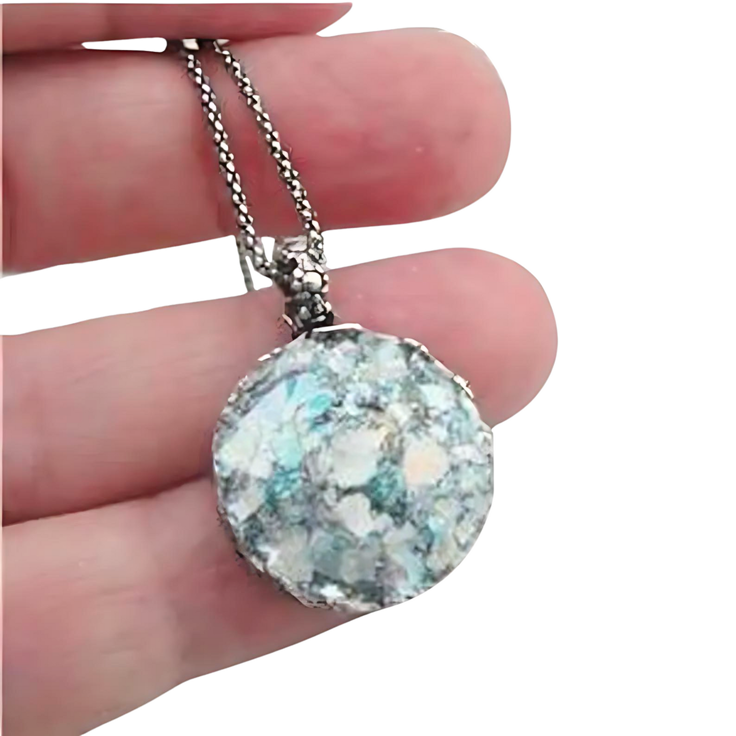 Handcrafted sterling silver pendant featuring a round Roman glass centerpiece in shades of light blue and silver. The unique, textured chain complements the pendant, creating a distinctive, artisanal look. Shown held in hand to display its intricate details and delicate craftsmanship