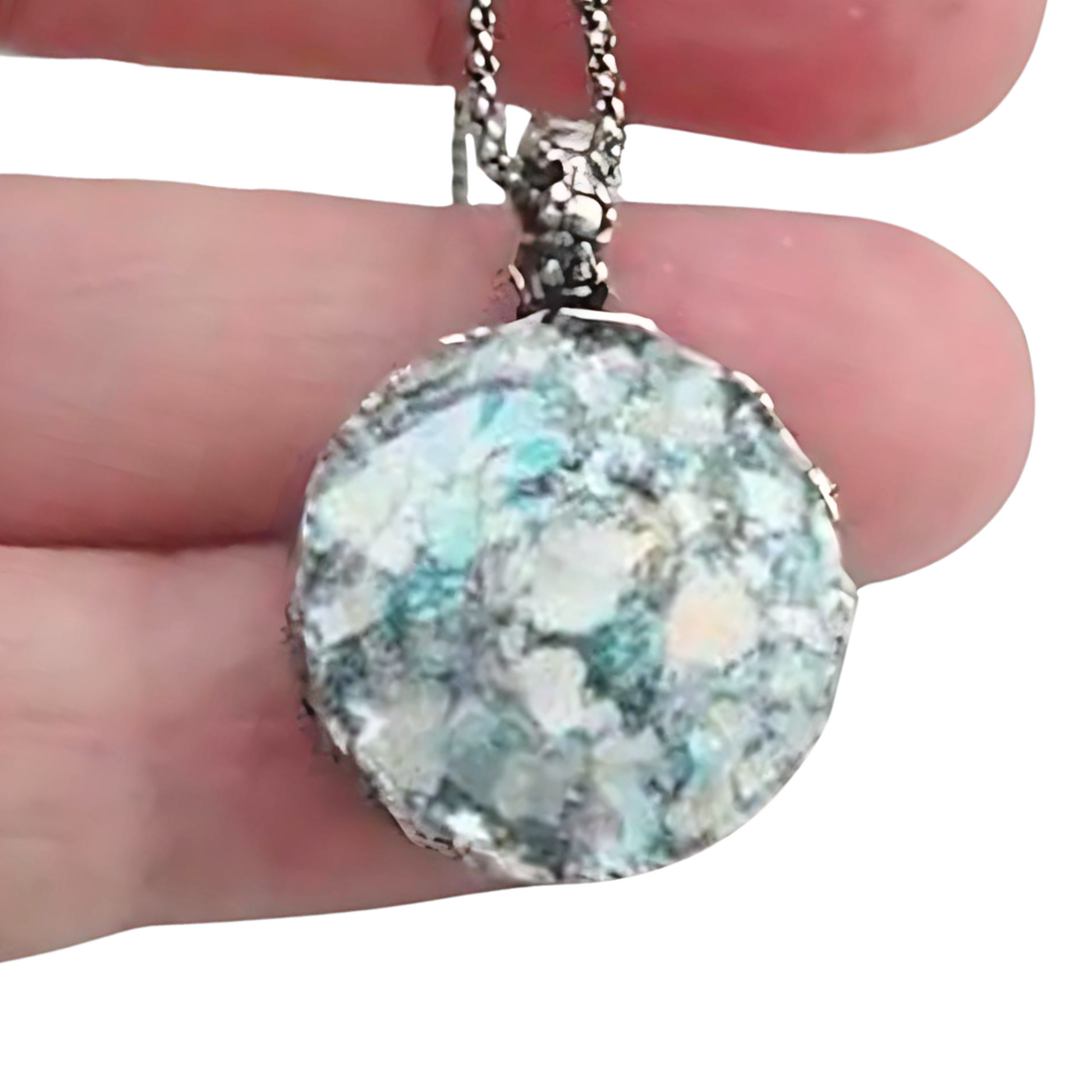 Handcrafted sterling silver pendant featuring a round Roman glass centerpiece in shades of light blue and silver. The unique, textured chain complements the pendant, creating a distinctive, artisanal look. Shown held in hand to display its intricate details and delicate craftsmanship