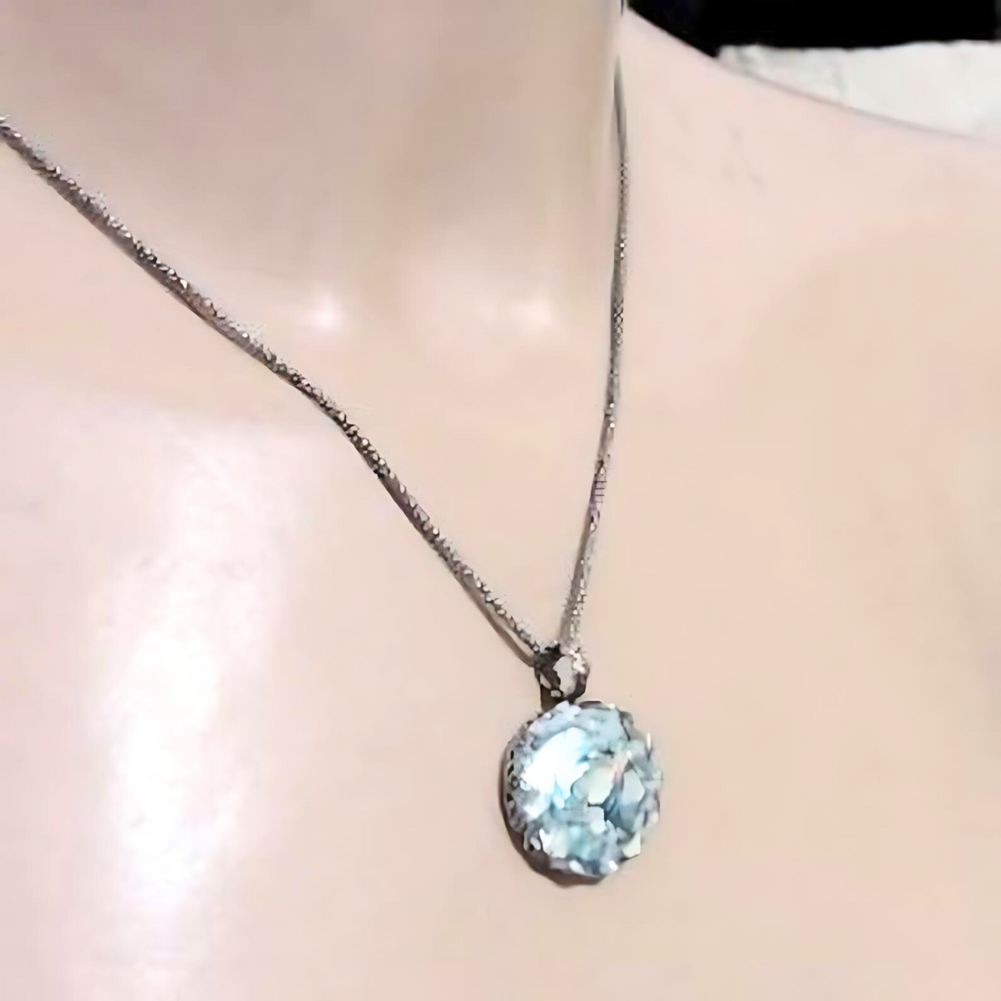 Handcrafted sterling silver pendant featuring a round Roman glass centerpiece in shades of light blue and silver. The unique, textured chain complements the pendant, creating a distinctive, artisanal look. Shown held in hand to display its intricate details and delicate craftsmanship