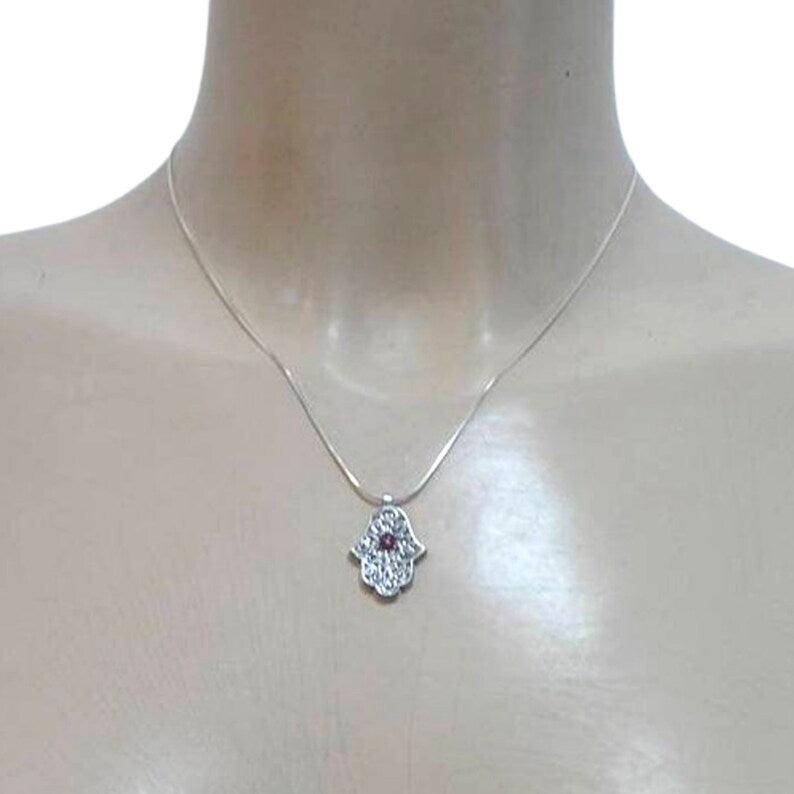 Sterling silver Hamsa pendant with intricate design and a natural garnet at the center, symbolizing protection and good luck. A meaningful and spiritual piece of jewelry, perfect for a gift and adding positive energy.