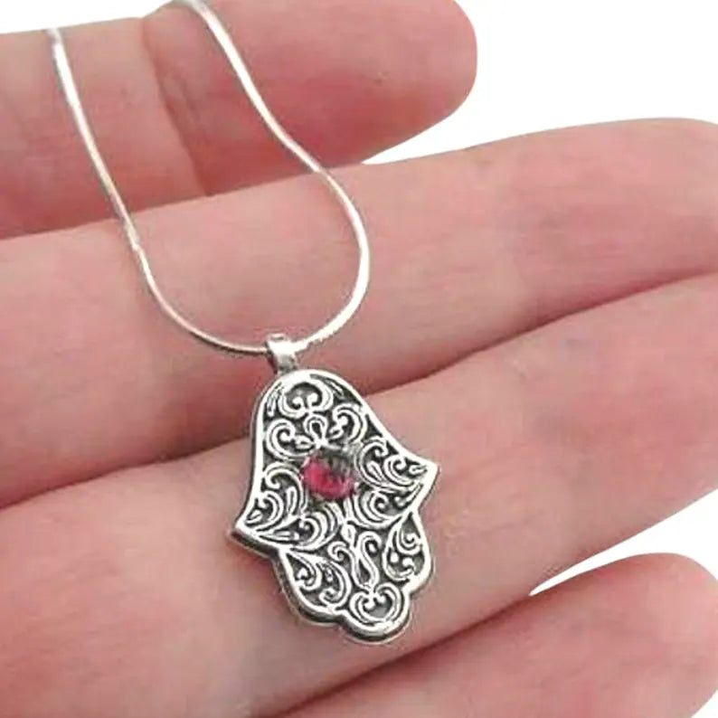 Sterling silver Hamsa pendant with intricate design and a natural garnet at the center, symbolizing protection and good luck. A meaningful and spiritual piece of jewelry, perfect for a gift and adding positive energy.