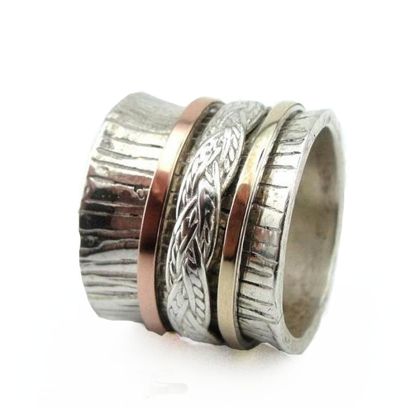 Wide sterling silver ring decorated with marked lines and swivel sterling silver, red and yellow gold bands.