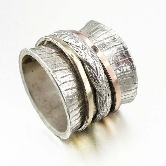 Wide sterling silver ring decorated with marked lines and swivel sterling silver, red and yellow gold bands.